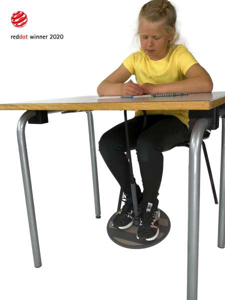 En pige sidde ved et bord og skriver i en bog imens hun bruger en SwnX Fodgynge Skole One 