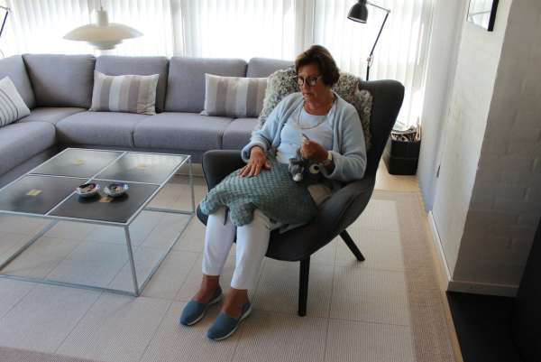 Person sidder i stol med Koko Nora vægttæppe Stor Manta – sansestimulerende hjælpemiddel til afslapning

