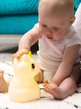 Baby i hvid body med lumipets natlampe enhjørning med gult lys