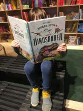 Barn sidder og læser i Boldens store bog om dinosaurer