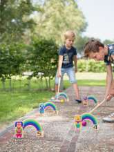 Børn spiller regnbue kroket ude i en have
