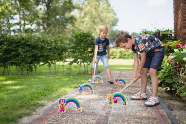 Børn spiller regnbue kroket ude i en have