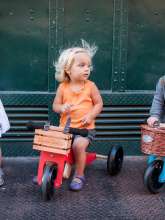 Barn kører på kinderfeets cykel med kasse på.
