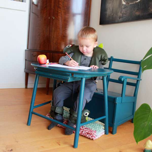 Barn sidder med sensorisk skulderpude Camo – hjælpemiddel til fokus, kropsro og sanseregulering i hverdagen

