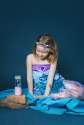 Pige i havfruekostume sidder med Petit Boum sanseflaske med lyd, havfrue