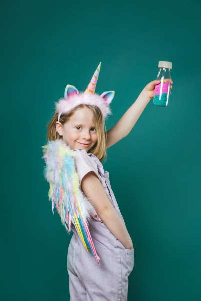Pige i enhjørningudklædning med Petit Boum sanseflaske med lyd, enhjørning