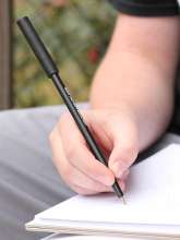 Person skriver med Ark's Write-n-Bite bidetop med kuglepen