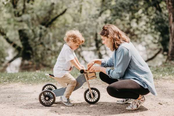 Barn sidder på Timy Tots Blue Slate løbecykel med voksen ved siden af