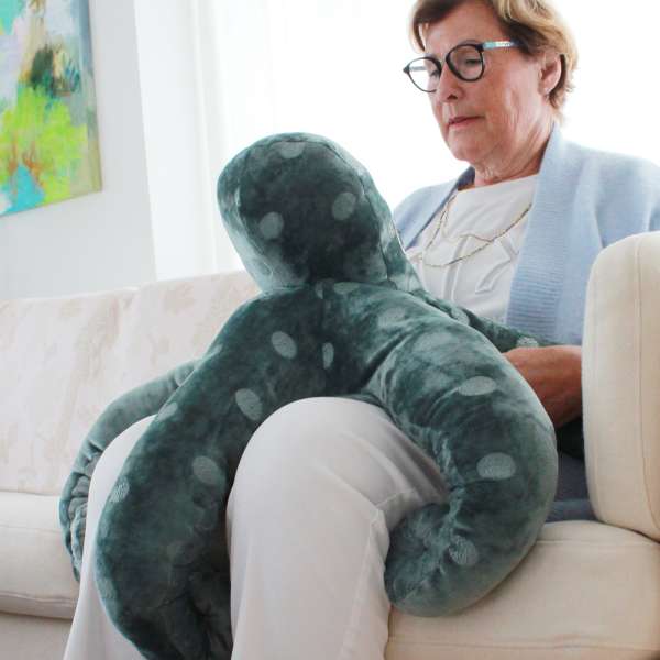 Kvinde sidder med Sansemotorisk tyngdetæppe Poul