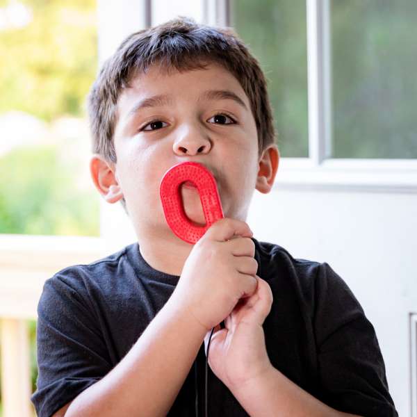 Barn bruger ARK Grabber Brick rød – tyggeredskab til ro og oral stimulering

