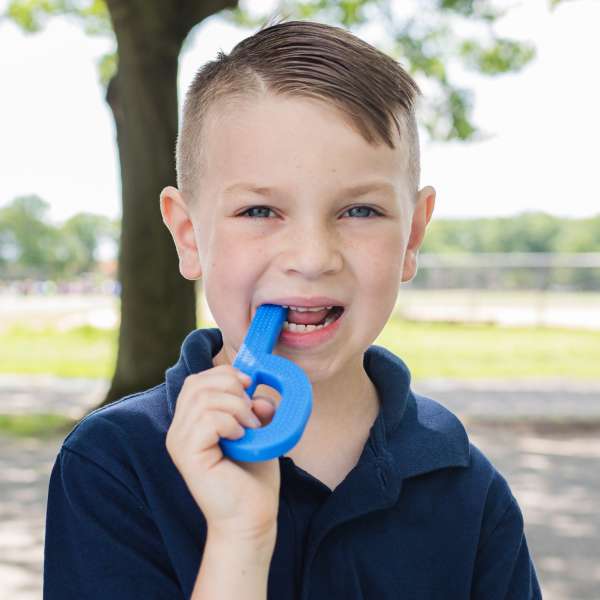 Barn bruger ARK Grabber Brick kongeblå – sansestimulerende bideredskab til fokus

