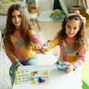 To pigen spiller men Smart Games IQ Twins ved et bord 