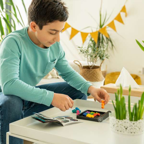 Dreng spiller men Smart Games IQ Perplex ved et sofabord 