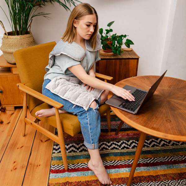 Kvinde sidder med skulderpude med tyngde – afslapning og velvære i hverdagen

