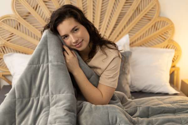 Person sidder med velourtæppe grå – tyngdetæppe til ro og afslapning

