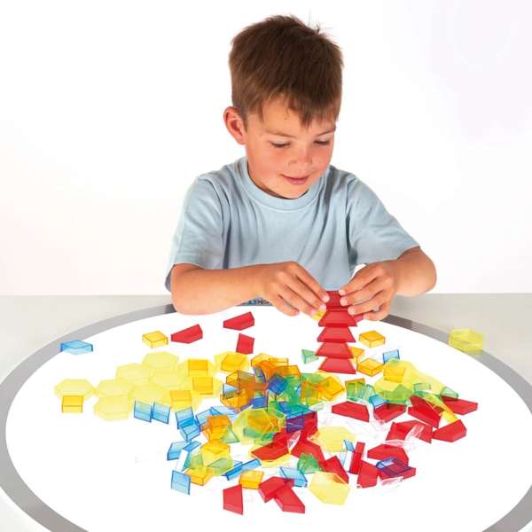 En dreng leger med Geometriske mønsterbrikker, 180 stk. på et bord 