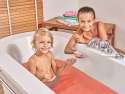 En dreng sidde i et badekar og leger med  Vandfarve badetablet i mens en pige sidde ved side af og leger med 