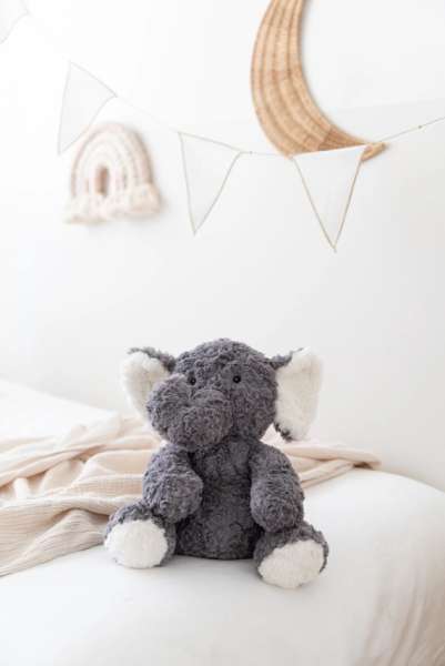Elefanten Eleanor siddende på seng – tryg og hyggelig bamse til børn

