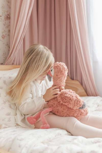 En pige og Flamingoen Francesca hygge sammen i en seng 