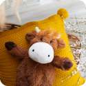 Sansebamse Warmies højlandsko ligge på en pude 