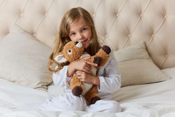 Sansebamse Warmies Liggende Rådyr hygger med en pige i en seng