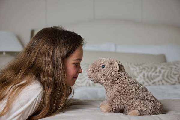 Sansebamse Warmies kapivar og en pige på en seng