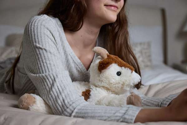 Sansebamse Warmies liggende ged sammen med en pige