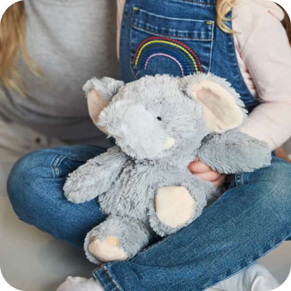 Barn krammer Warmies-elefant, demonstrerer berøring og trøst