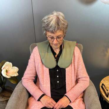 Sensorisk skulderpude Liz – kvinde sidder med tyngdepude for ro

