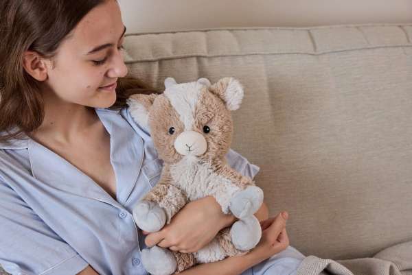 Sansebamse Warmies siddende ged sidde i en sofa sammen med en pige