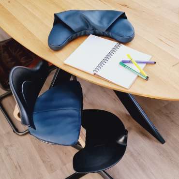 Oliz siddepude placeret på stol ved bord – giver komfort og støtte til børn i højstol

