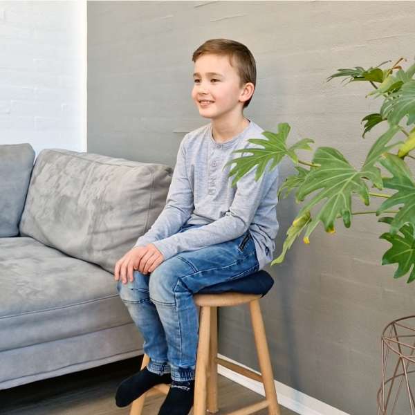 Barn sidder på skammel med Oliz siddepude Eva – forbedrer komfort og kropsholdning

