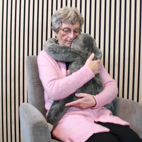 
Ældre person sidder med sansebamse Store Bent i armene – beroligende og tryghedsskabende sansedyr

