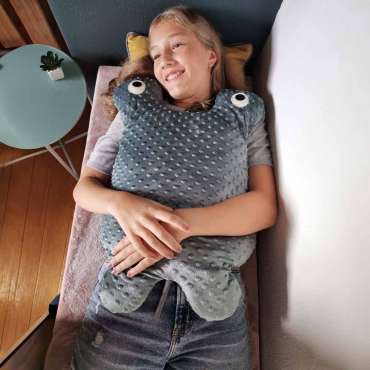 Person ligger afslappet med Koko Nora vægttæppe Stor Manta – beroligende og sansestimulerende tyngdetæppe

