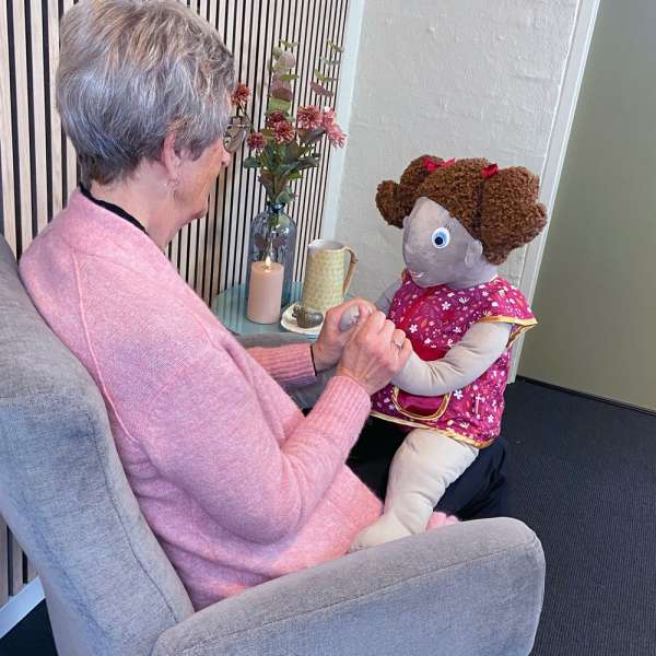 Demensdukke Lille Lise – kvinde holder og taler med dukke

