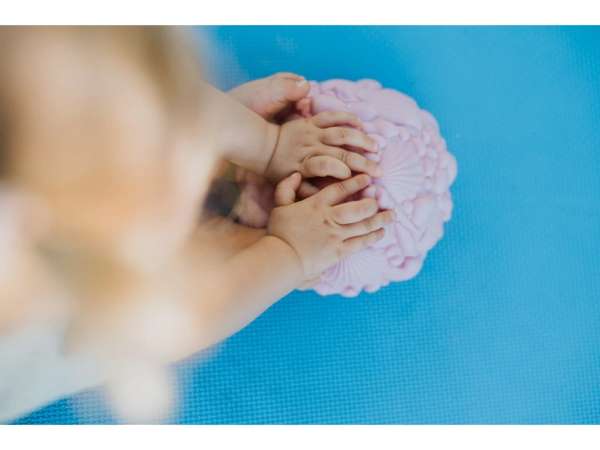 Barn rører strandskaller balancesten rosa – taktil sansestimulering

