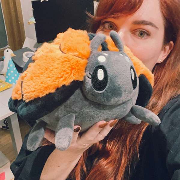 Person holder Monark sommerfugl plush bamse tæt på ansigt – stor orange kawaii sommerfugl i brug

