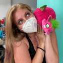 Person holder Dragefrugt drage plush bamse op ved kinden – pink kawaii drage med grønne vinger og fluffy design i brug

