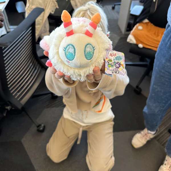 Person holder møl bamse i kage design, blød og sjov plys bamse med farverige detaljer

