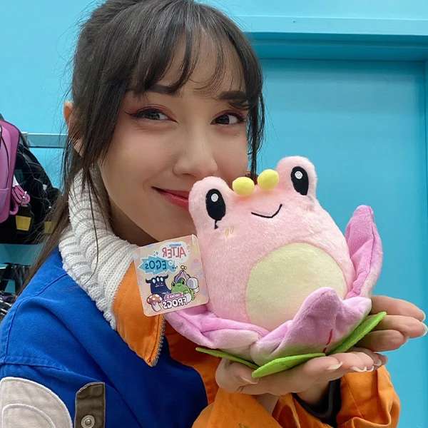 Person holder lotusfrø bamse i hænderne, blød og sød plys bamse med blomsterdesign

