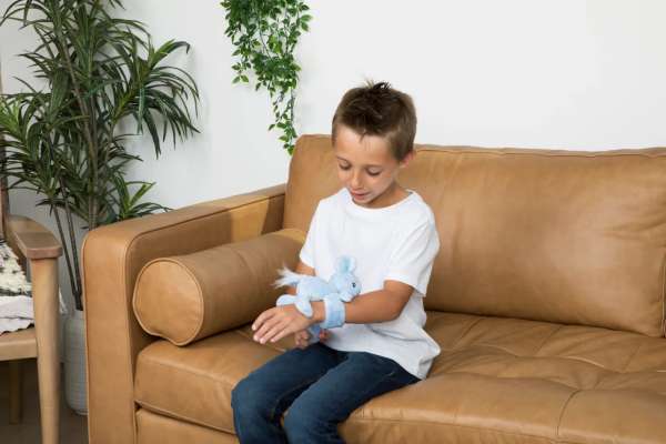 En dreng sidde på en sofa samme med Hug Baby Emory