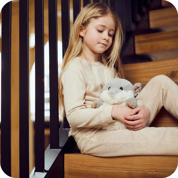 Sansebamse Warmies Grå Hamster sider på en trappe sammen med en pige