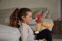 Sansebamse Warmies® brun høne og en pige sidder på gulvet foran en sofa