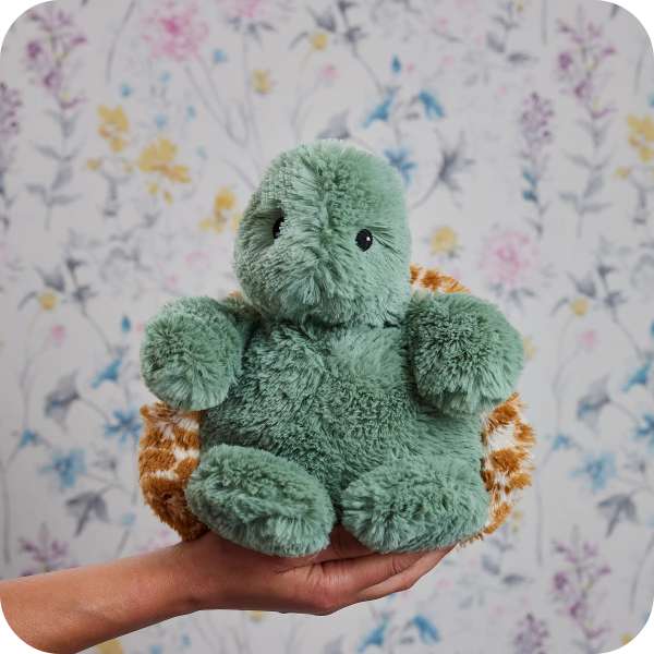 Sansebamse Warmies® baby skildpadde sidder på en hånd