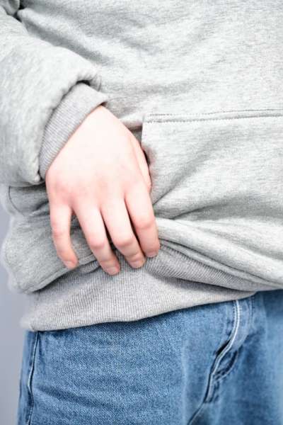 Detalje af lomme på grå hoodie, praktisk frontlomme på komfortabel tyngdehoodie til børn

