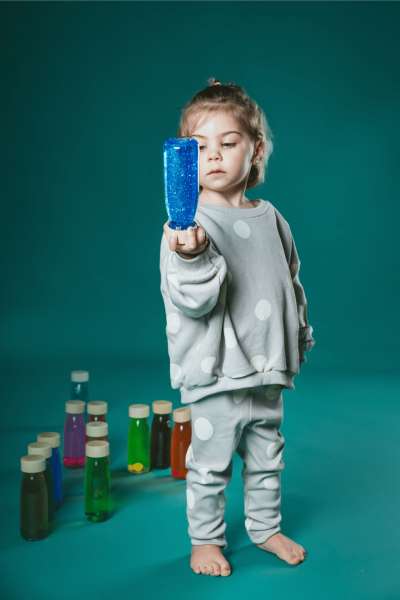 De tre sanseflasker vist på bord, hvor farver og flydende elementer skaber visuel effekt