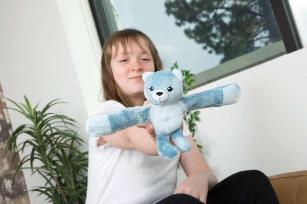 Barn leger med blå krammebamse med lange arme, blød tøjbamse designet til tryghed og leg

