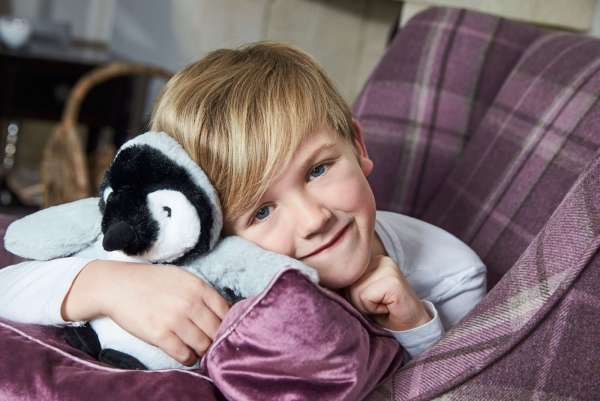 Sansebamse Warmies® baby pingvin sammen med en dreng 