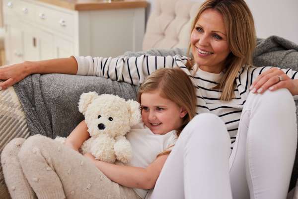 Sansebamse Warmies® bjørn, cremefarvet sammen med en pige og hende mor 