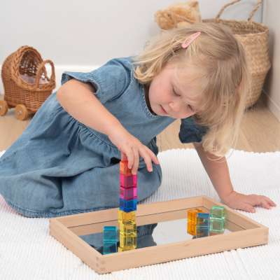 En pige leger med tickit® Gem Cubes på en bakke hvor der er spejl i
